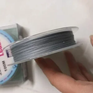 Một người đang cầm trên tay cuộn dây dù câu cá Daiwa SW Durabra Leader, cho thấy độ mượt và đều của sợi PE.