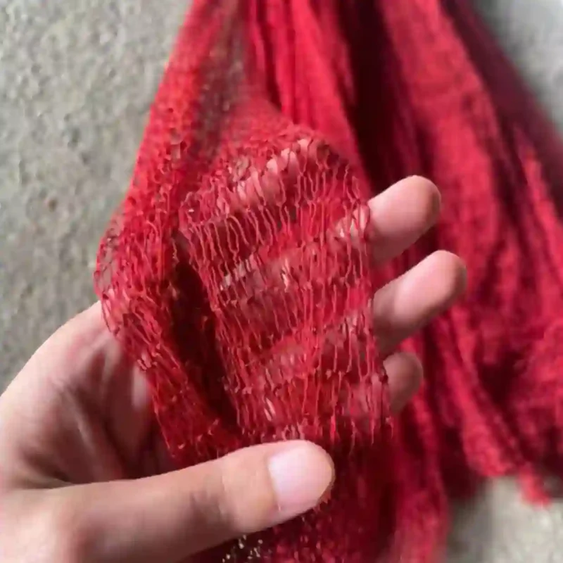 Cận cảnh sợi lưới tàng hình màu đỏ đang được cầm trên tay, cho thấy chất liệu lưới rất mảnh và mềm mại.