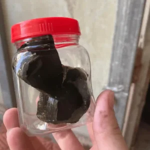 Một hũ keo bẫy chim màu đen, dạng đặc, siêu dính đựng trong lọ nhựa trong suốt.