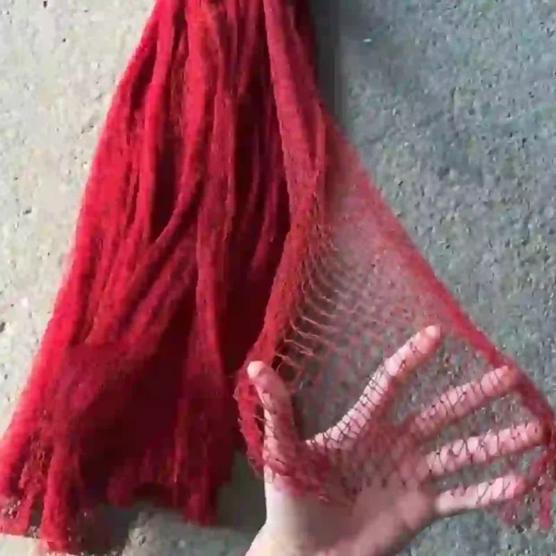 Bàn tay kéo căng một phần của tấm lưới tàng hình màu đỏ để thể hiện mắt lưới và độ co giãn của sợi.