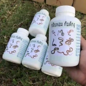 Một tay đang cầm lọ thuốc đuổi rắn dạng bột, phía sau là nhiều lọ khác trên bãi cỏ.