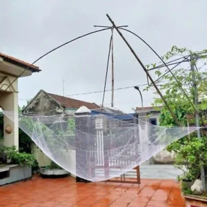 Một chiếc vó kéo cá hoàn chỉnh được bung ra trên khung đỡ bằng tre/thép trong sân nhà.