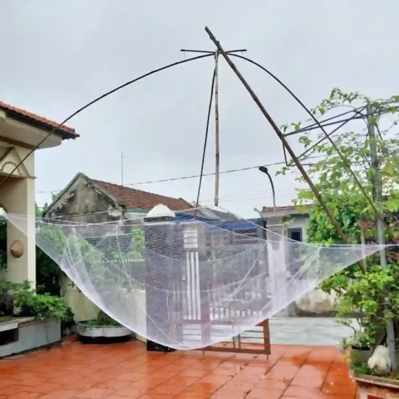 Một chiếc vó kéo cá hoàn chỉnh được bung ra trên khung đỡ bằng tre/thép trong sân nhà.